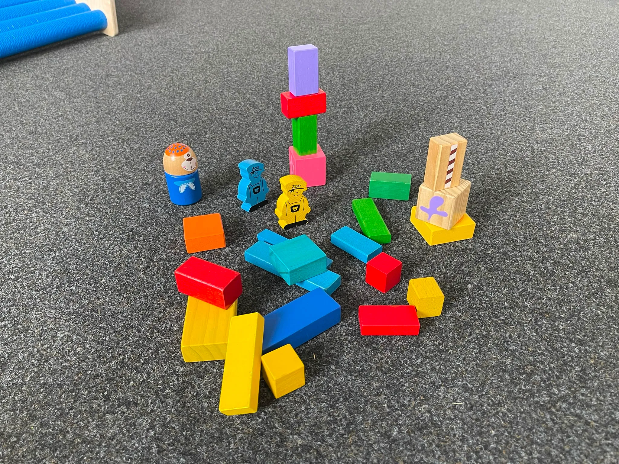Bunte Holzbausteine und Spielfiguren auf dem Teppich