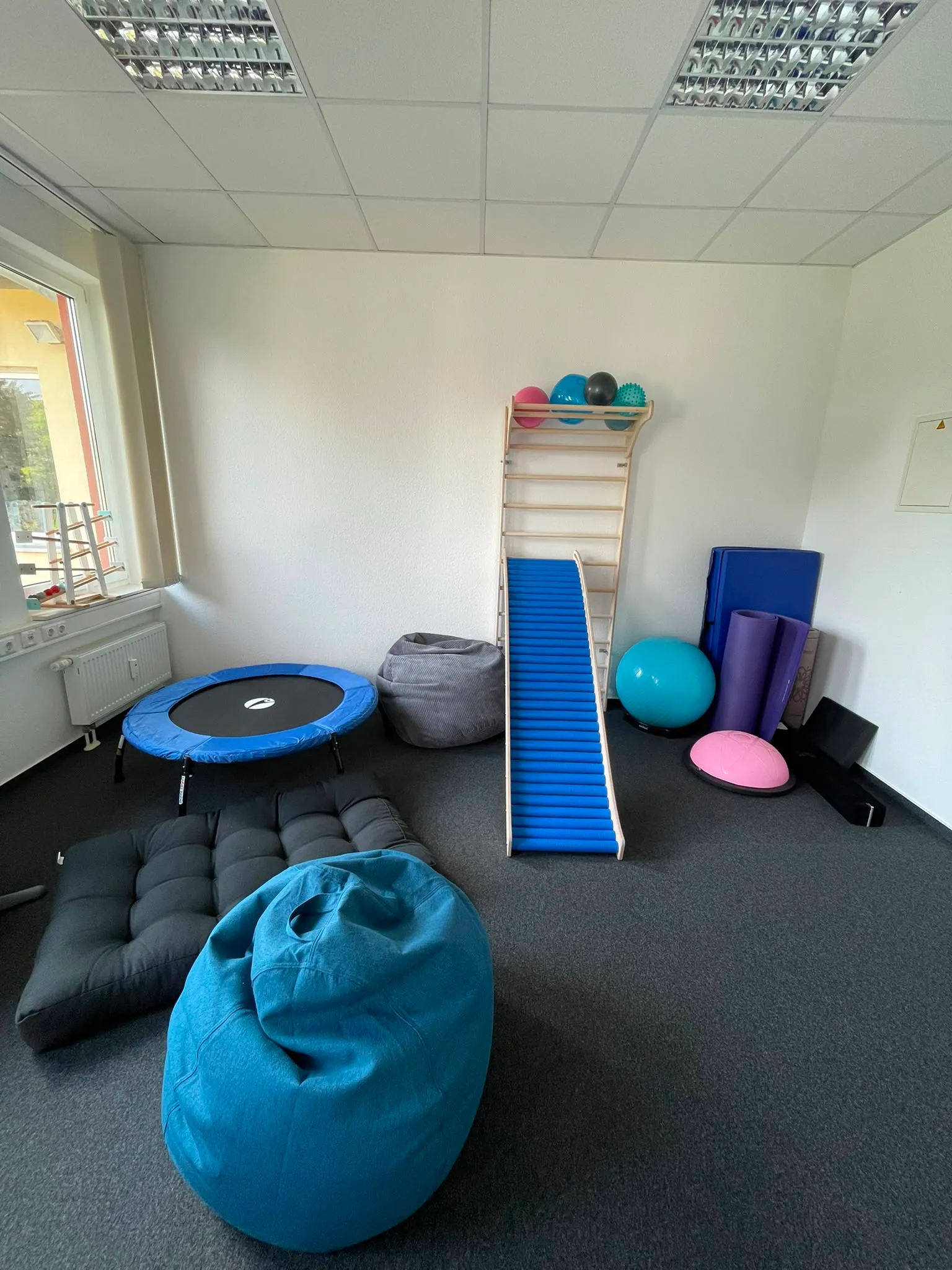 Behandlungsraum mit Trampolin, Sprossenwand, Rutsche und Sitzsack